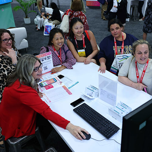 Group sits around table and looks at computer screen.