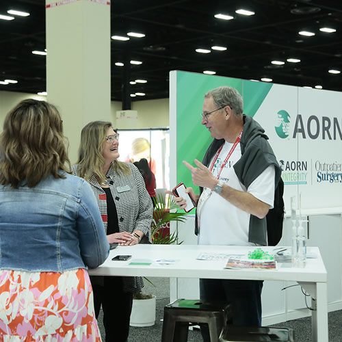 People talk at booth in Expo Hall.