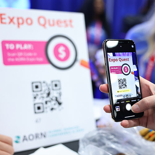 Person uses phone to scan QR code on Expo Quest sign.